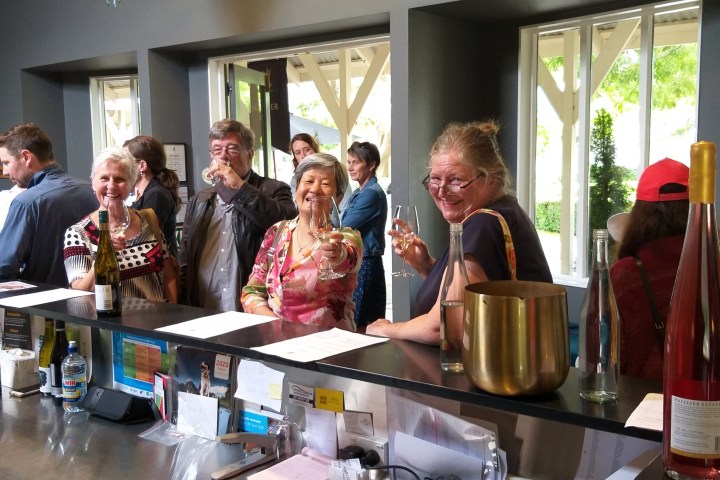 a group of people sitting at a table with a bottle of wine