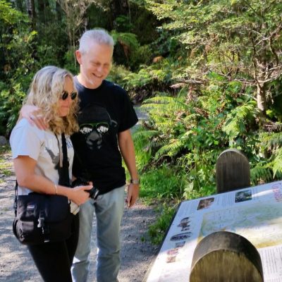 a young boy standing next to a tree